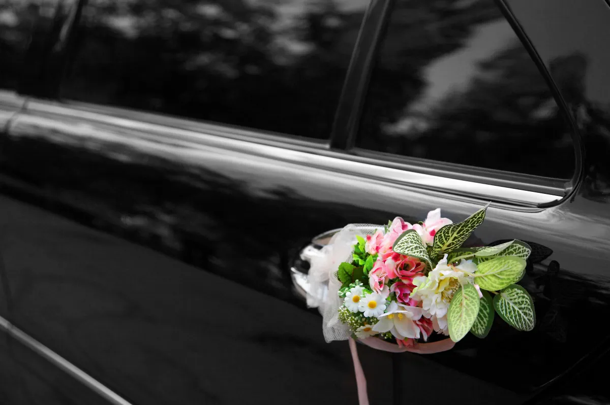 Un bouquet de fleurs accroché à la poignée d’une voiture de mariage