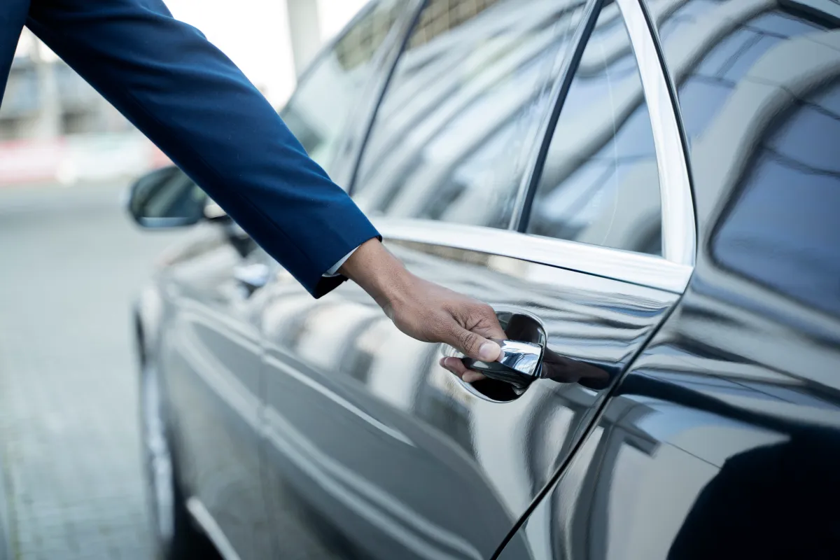 Un chauffeur ouvre la portière arrière d’une berline noire